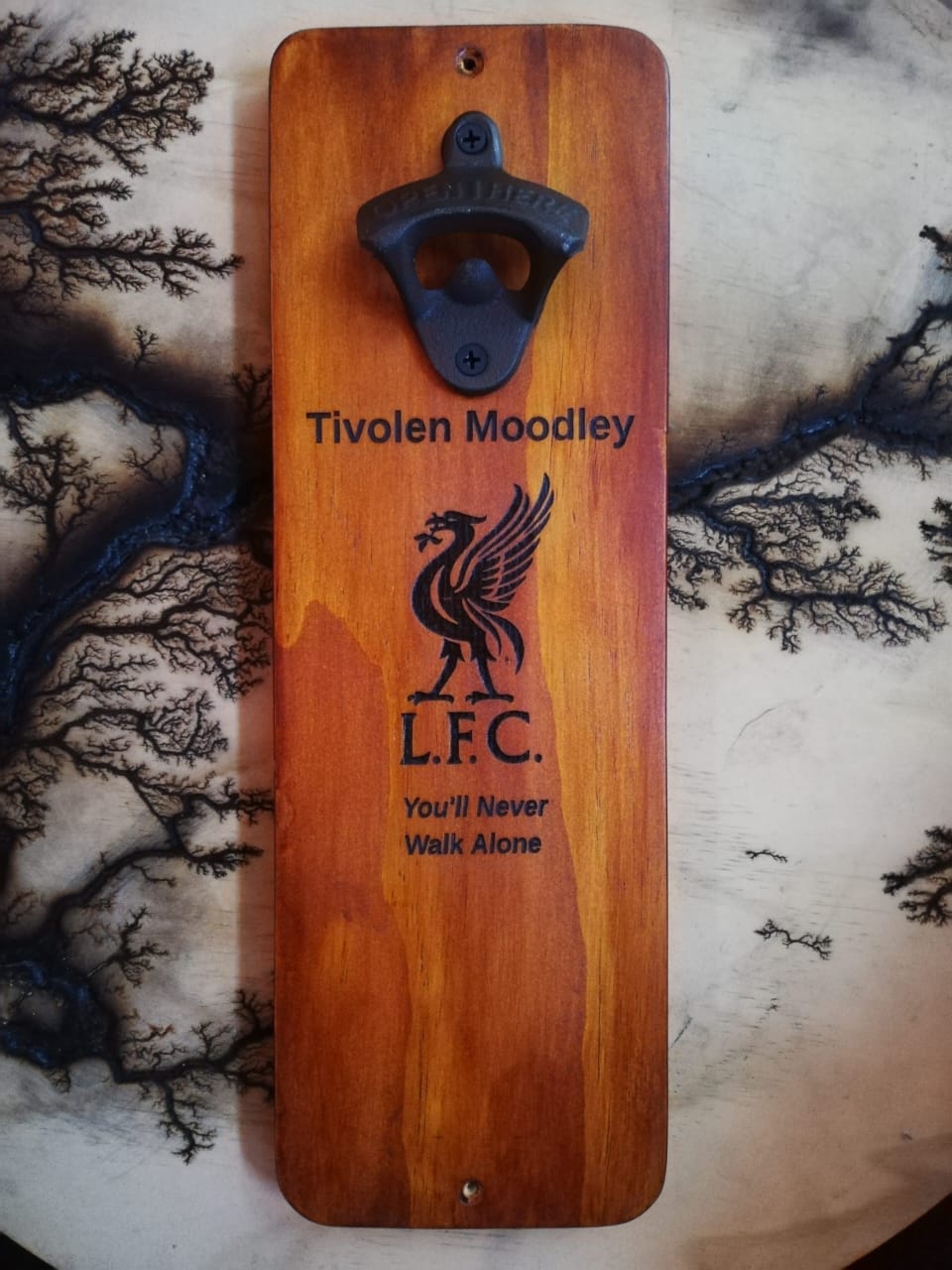 Wooden bottle opener in action with cap catch