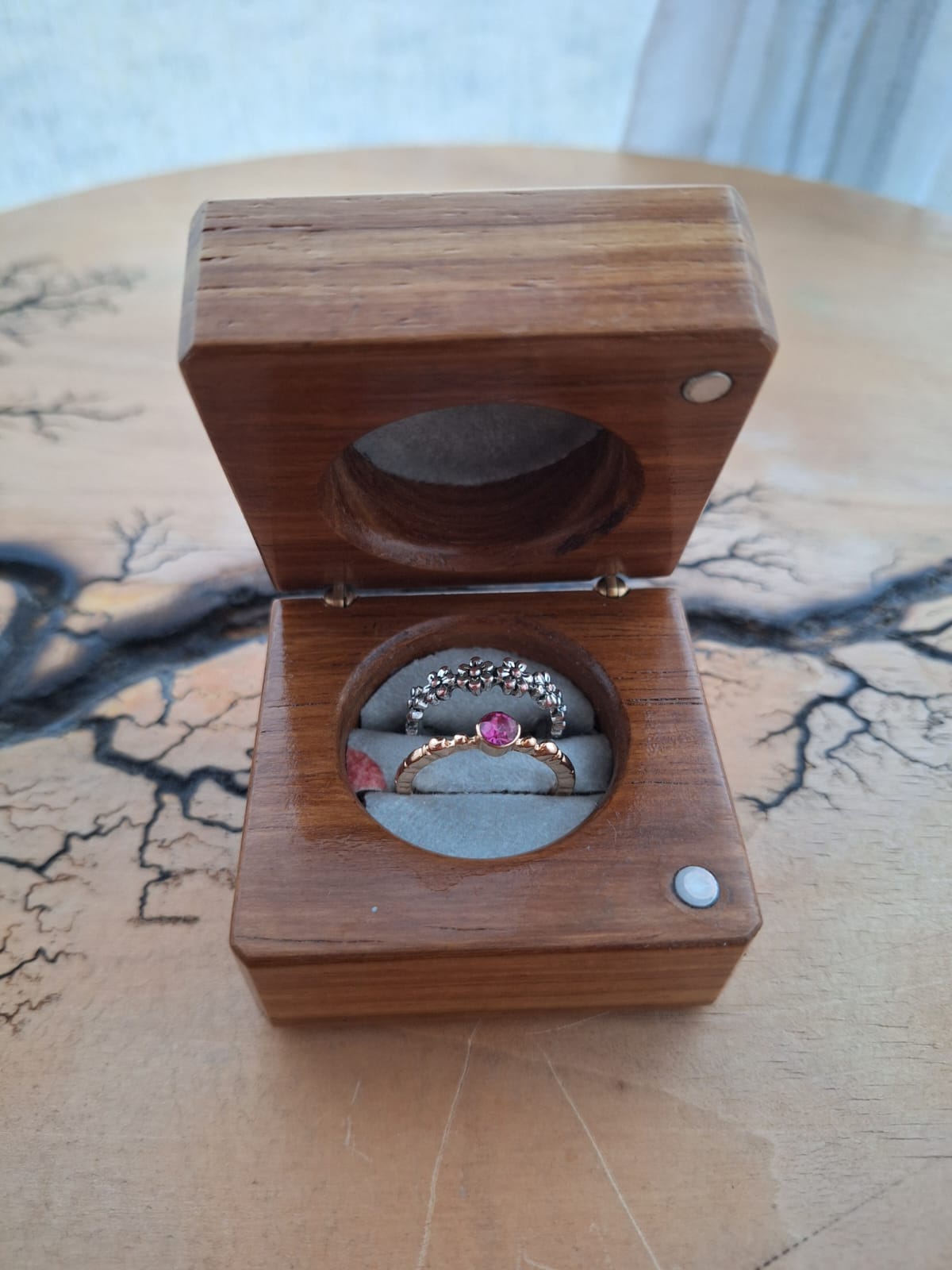 Open wooden ring box holding two rings on midnight-blue velvet